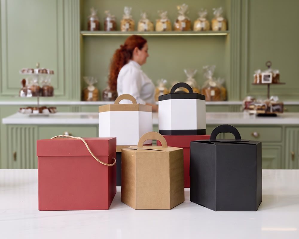 Scatole cubiche e esagonali per panettoni e pandori su un piano bianco di un laboratorio di pasticceria